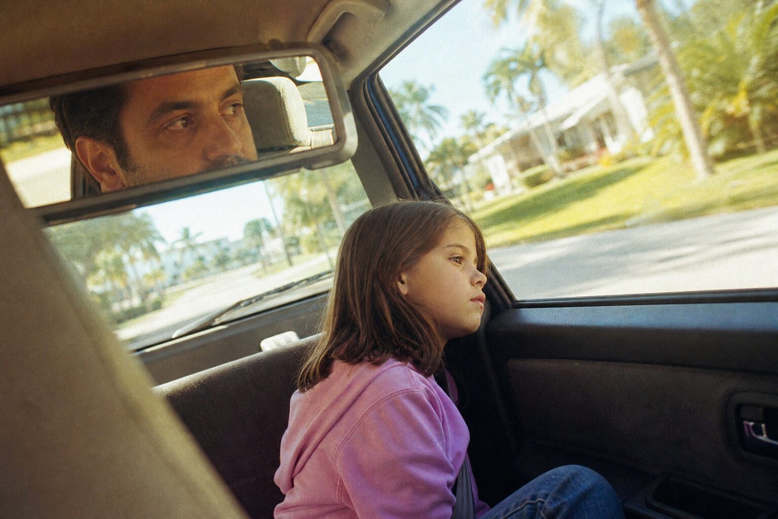 車の窓から外を眺める少女と運転する父親