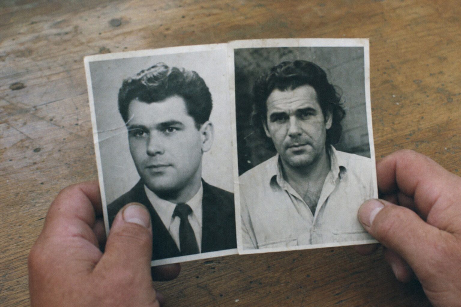 2枚のモノクロ写真を並べて見比べる男性の手
