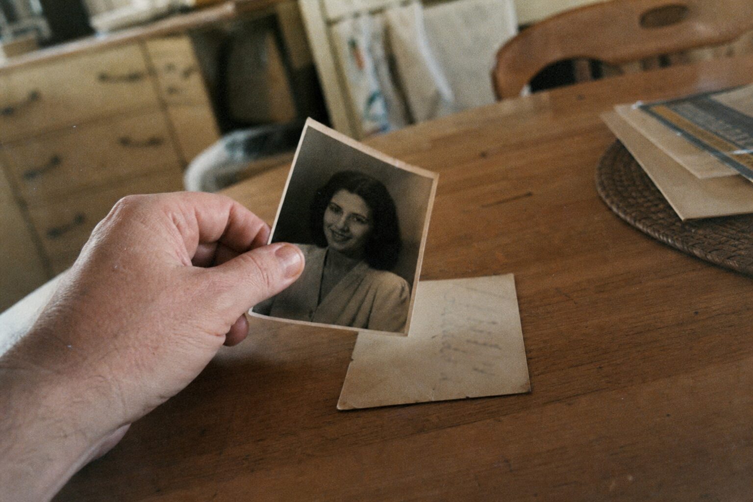 写真の裏に書かれた文字を確認する女性の指